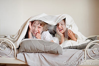 Two children, brother and sister, squirmy on the bed in the bedroom. Stock Photo