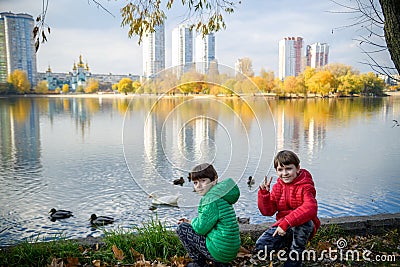 Two children feed the wild ducks and shoal of small fish in azur Stock Photo