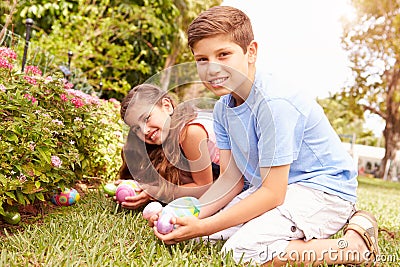 Two Children Having Easter Egg Hunt In Garden Stock Photo