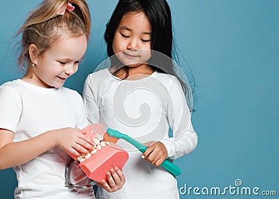 Two children kids friends with toothbrush hold big dental implant model try to brush teeth Stock Photo