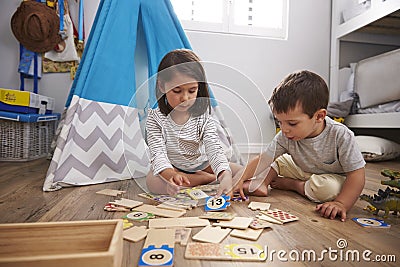 Two Children Playing Number Puzzle Game Together In Playroom Stock Photo