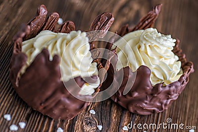 Two chocolate desserts filled with white cream on wooden table, dessert with white hearts for valentines day Stock Photo