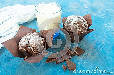 Two chocolate muffins, black chocolate and a glass of milk on a blue background Stock Photo