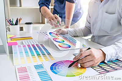 Two colleague creative graphic designer working on color selection and color swatches, drawing on graphics tablet at workplace wi Stock Photo