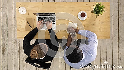 Two colleagues discussing data on laptop putting down notes Stock Photo