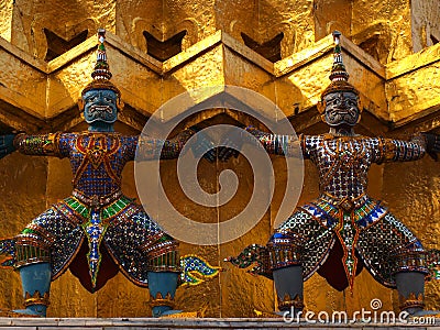 Two colorful detailed thai stone sculpture guardians holding the Bangkok temple walls, Thailand Stock Photo