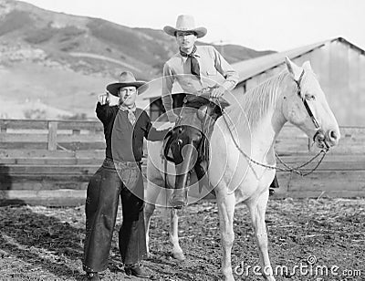 Two cowboys and a white horse Stock Photo