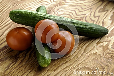 Two cucumbers and three tomatoes on a wooden surface Stock Photo