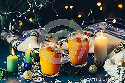 Two cup of hot spicy tea with sea buckthorn, cinnamon and star anise, branches of pine and spruce, candles and holiday decor, Stock Photo