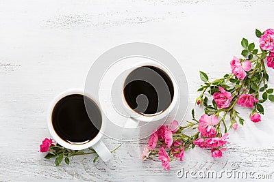 Two cups of black coffee and branch of small pink roses. Stock Photo