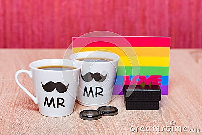 Two cups of coffee, gay flag and a black gift box with marriage ring Stock Photo