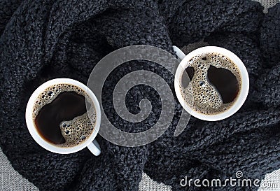 Two cups of coffee wrapped in black woolen scarf Stock Photo