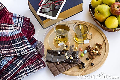 Two cups of herbal tea with fruit,old book,tablet,chocolate,nuts and blanket on white. Stock Photo