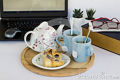 Two cups of herbal tea with teapot,old book,snack and laptop on white Stock Photo