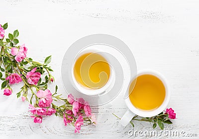 Two cups of tea and branch of small pink roses. Stock Photo