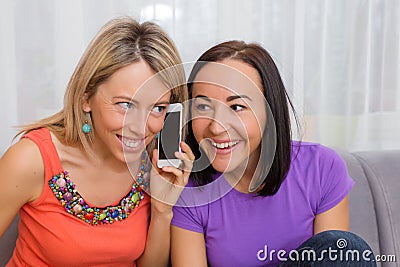 Two curious women listening to phone conversation Stock Photo