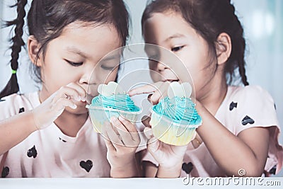 Two cute asian child girls having fun to eat blue cupcake Stock Photo