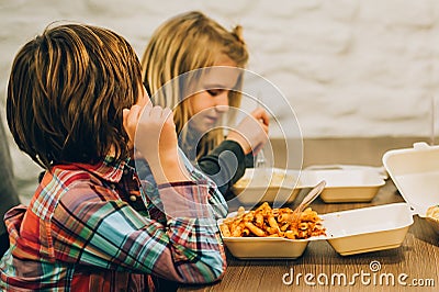 Two cute children eats spaghetti pasta in fast food restaurant Stock Photo