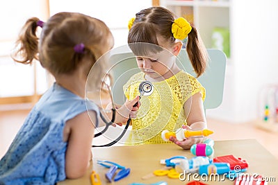 Two cute children playing doctor and hospital using stethoscope. Friends girls having fun at home or preschool. Stock Photo