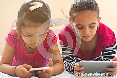 Two cute Indian children busy in watching Mobile phone on bed. Stock Photo