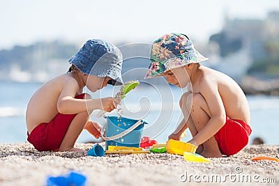 Two cute kids, playing in the sand on the beach Stock Photo