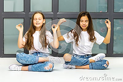 Two cute little girls meditate near the window. Stock Photo