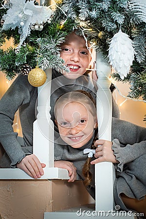 Two cute little girls on the stairs, looking over the railing. sisters waiting for a surprise for christmas Stock Photo
