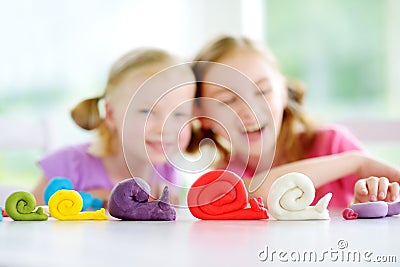 Two cute little sisters having fun together with colorful modeling clay at a daycare Stock Photo