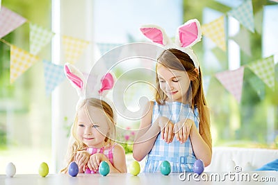 Two cute little sisters wearing bunny ears playing egg hunt on Easter Stock Photo