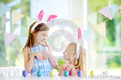 Two cute little sisters wearing bunny ears playing egg hunt on Easter Stock Photo