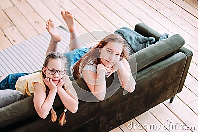 Two cute smiling girls children friends tweens sitting on sofa at home Stock Photo