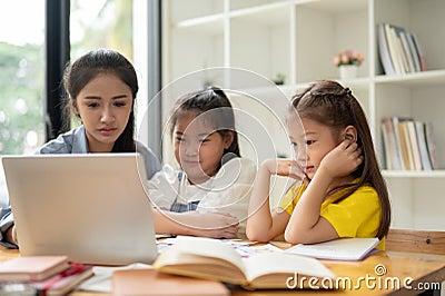 Two cute young Asian girls are focusing on studying with a private teacher at home Stock Photo