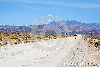 Two cyclists riding on a dirt road in the Karoo Editorial Stock Photo