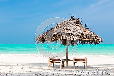 Two deck chairs and umbrella on tropical beach. Stock Photo