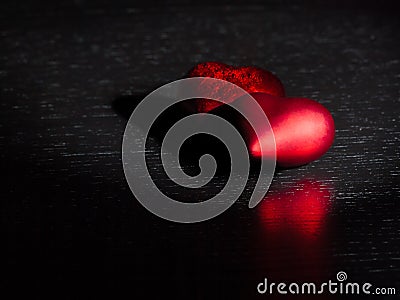 Two decorative red hearts on black dark light and on wood table, concept of valentine day Stock Photo