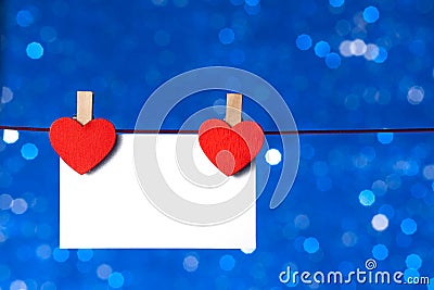 Two decorative red hearts with greeting card hanging on blue light bokeh background, concept of valentine day Stock Photo