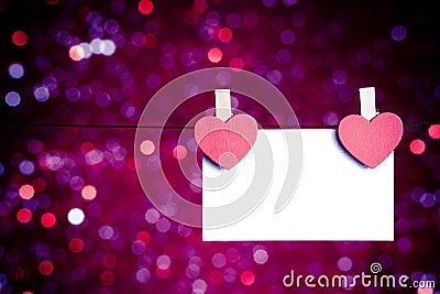 Two decorative red hearts with greeting card hanging on blue and violet light bokeh background, concept of valentine day Stock Photo