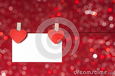 Two decorative red hearts with greeting card hanging on red light bokeh background, concept of valentine day Stock Photo