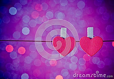 Two decorative red hearts hanging against blue and violet light bokeh background, concept of valentine day Stock Photo