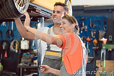 Two dedicated auto mechanics smiling while checking the wheels of a tuned car Stock Photo