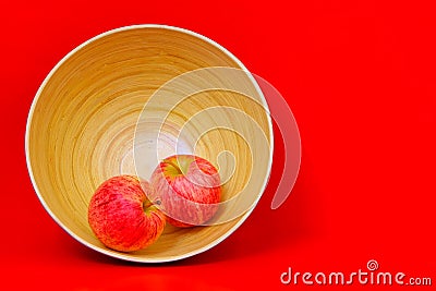 Pair of new zealand red apples in a bamboo pot against red background Stock Photo