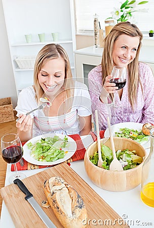 Two delighted friends eating salad in the kitchen Stock Photo