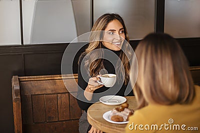 Two delighted women girlfriends drinking coffee and talking during meeting in cozy cafe Stock Photo