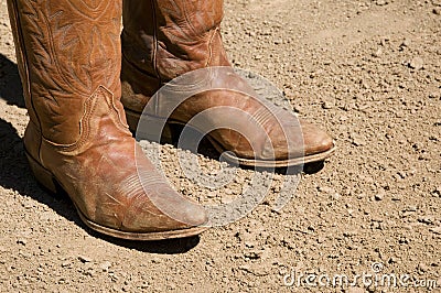 Two dirty western cowboy boots standing on dirt ground Stock Photo