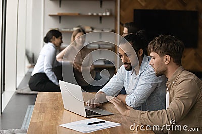 Two diverse male employees working on project together using laptop Stock Photo