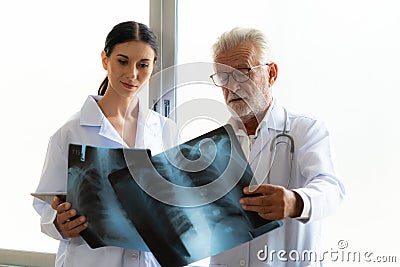 Two doctors examine radiograph for medical xray diagnosis in sterile room. Stock Photo