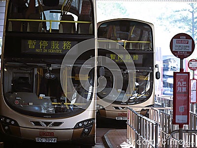 Double-decker buses parked at a bus stop in Hong Kong, with a street sign in the background Editorial Stock Photo