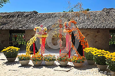 Two dragon costume for the celebration of the Asian New Year. Vases with live yellow flowers around dragons - new year symbol. Stock Photo