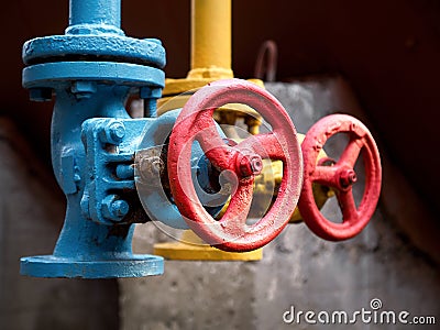 Two drain valves blue and yellow with red steering wheels over b Stock Photo