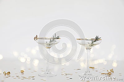 Two drinking glasses with champagne, bubbly wine. White table. Golden star shape confetti. Blurred background with bokeh Stock Photo